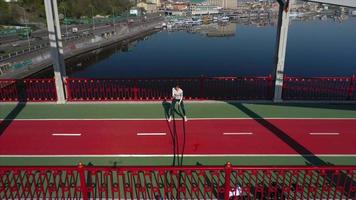 Woman exercises with battle ropes on a pedestrian track bridge video