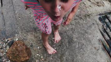Kid playing with water drips at the beach, washing hand and face video