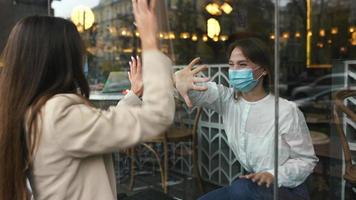 Girl friends meet and talk through window video