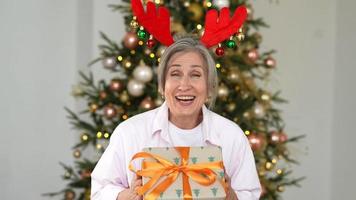 Woman with christmas present smiles at camera video