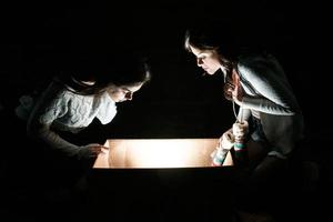 las hermanas abren una caja con un regalo de navidad y miran fascinadas dentro foto