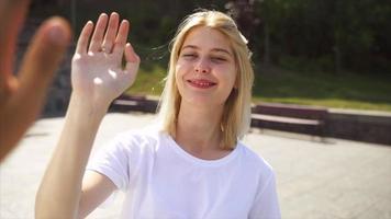 junge blonde frau oder jugendlich schaut auf und high fives person außerhalb der kamera video