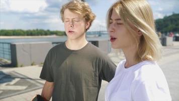 Teenage boy and girl walk and talk on a bight sunny day in outdoor city space video