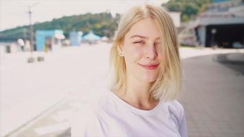 Teen girl with blonde hair stands outside in an open public space video