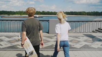 deux adolescents marchent vers une balustrade pour regarder au-dessus de l'eau video