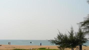les gens marchent le long de la plage au bord de la mer. l'avion approche pour atterrir à l'aéroport. aéroport international de phuket en thaïlande video