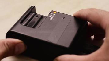 the man inserts the camera battery into the charger, the charging indicator flashes. video