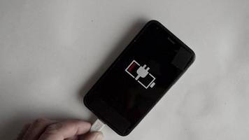the man holds the charger cable,the smartphone indicator shows the battery charging. video
