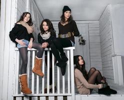 Four stylish models posing sitting on the fence. Christmas background photo