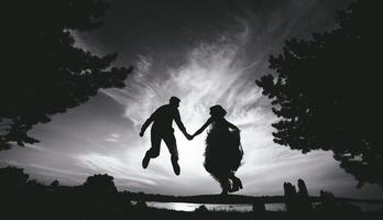 groom and bride jumping against the beautiful sky photo