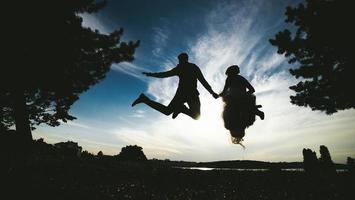 groom and bride jumping against the beautiful sky photo