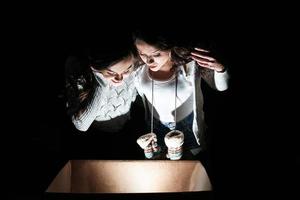 las hermanas abren una caja con un regalo de navidad y miran fascinadas dentro foto