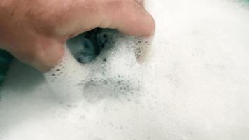mano humana creando espuma con esponja. preparación de líquido espumoso y jabonoso para la limpieza. video