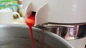 Red freshly squeezed juice leaks from spout of electric juicer. video