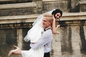 el novio lleva a la novia en sus brazos foto