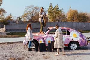 mujeres jóvenes posando cerca de un viejo auto decorado foto