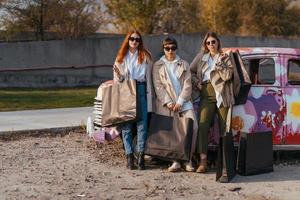 mujeres jóvenes posando cerca de un viejo auto decorado foto