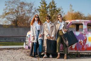 mujeres jóvenes posando cerca de un viejo auto decorado foto