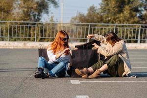 mujeres jóvenes con bolsas de compras sentadas en el estacionamiento foto