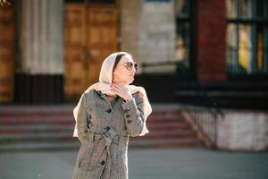 girl in a coat posing on building background photo