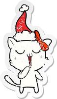 distressed sticker cartoon of a cat wearing santa hat vector