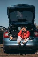 joven atractiva descansando en el maletero de un coche foto