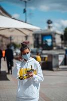 mujer joven sosteniendo café con máscara médica protectora foto