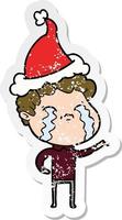 distressed sticker cartoon of a man crying wearing santa hat vector