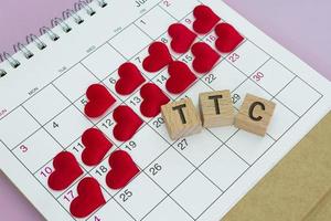 TTC word on wooden block with red heart shape on calendar. Trying To Conceive. photo