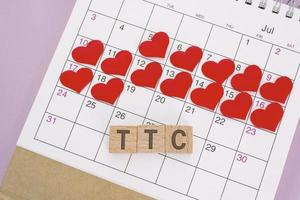 palabra ttc en bloque de madera con forma de corazón rojo en el calendario. tratando de concebir. foto