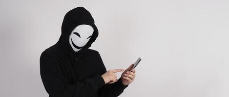 hacker anónimo y mascarilla con smartphone en la mano. foto