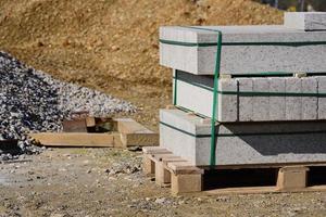 On a construction site, in front of piles of gravel and sand, there is a pallet with concrete blocks photo