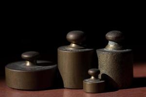 Several metal weights stand in front of a dark background with space for text photo
