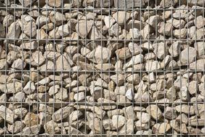 Background and texture of many rough stones lying in a metal stone cage forming a wall photo