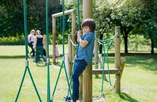 Active kid holding robe in playground, Child enjoying outdoors activity in a climbing adventure park on sunny day summer, Cuteyoung boy having fun on a public playground. photo