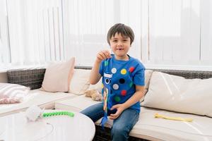 High key happy kid stay at home lying on sofa playing Koinobori Carp streamers,Child boy doing Japanese fish kite in sunny day summer, Distance education or Home schooling photo