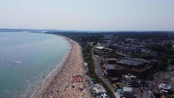 Frente a la playa con vistas al mar en ángulo alto con gente en la ciudad de Bournemouth, Inglaterra, Reino Unido, imágenes aéreas del océano británico video