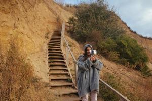 mujer joven toma una foto en un teléfono inteligente del paisaje marino