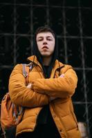 Young adult man in a yellow jacket walks on a city street photo