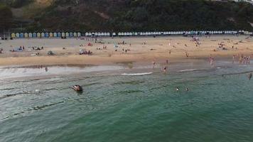 Frente a la playa con vistas al mar en ángulo alto con gente en la ciudad de Bournemouth, Inglaterra, Reino Unido, imágenes aéreas del océano británico video