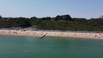 Frente a la playa con vistas al mar en ángulo alto con gente en la ciudad de Bournemouth, Inglaterra, Reino Unido, imágenes aéreas del océano británico video