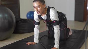 EMS training. Girl doing exercises in a suit with cables. photo
