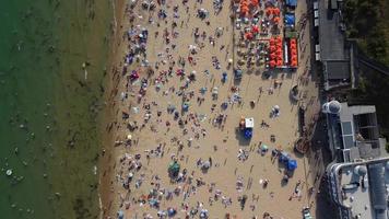 Vista de alto ângulo para o mar em frente à praia com pessoas na cidade de bournemouth, na inglaterra, reino unido, imagens aéreas do oceano britânico video