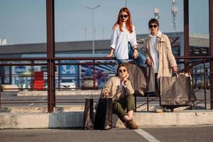 mujeres jóvenes con bolsas de compras en una parada de autobús foto