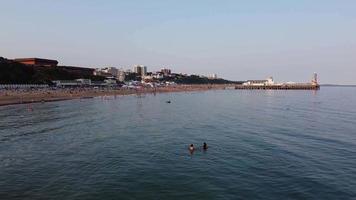 Frente a la playa con vistas al mar en ángulo alto con gente en la ciudad de Bournemouth, Inglaterra, Reino Unido, imágenes aéreas del océano británico video