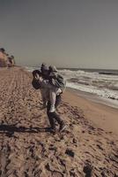 Man carries his girlfriend on back, couple having fun on the seashore photo