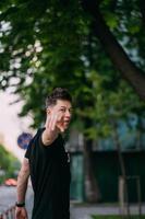 Young adult man in a black t-shirt and jeans walks on a city street photo