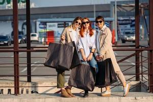 mujeres jóvenes con bolsas de compras en una parada de autobús foto