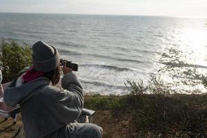 mujer joven toma una foto en un teléfono inteligente del paisaje marino