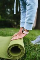 Close-up of woman folding roll fitness after working out in the park photo